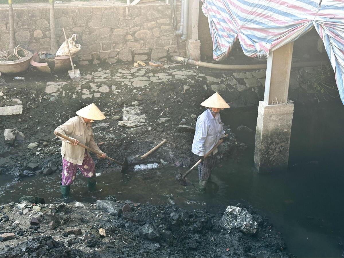 川に溜まった泥を掻き出しているノンラーを被った作業員の方たち。