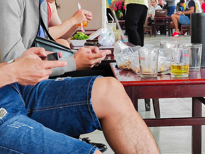 友達とスマホゲーム＆持ち込みごはんを頂く若者